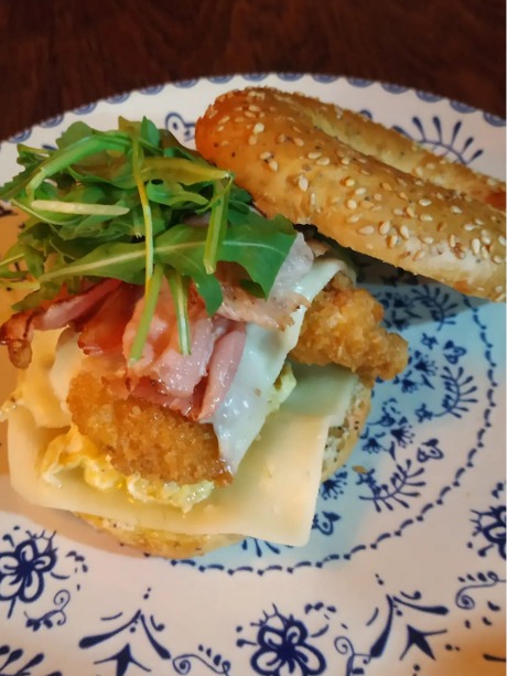Carta de Cafeterías en Pontevedra, Cafetería El huerto del cura pontevedra, Bagel de pollo empanizado, queso en loncha, huevo revuelto, bacon, tomate aliñado y rúcula con vinagre de Módena